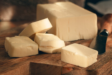 butter briquette, on wrapping paper, wooden chopping board and butter knife,breakfast, rustic style, no people,