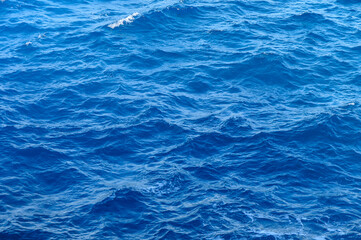 Obraz premium Vibrant turquoise waves dancing under the sunlight off the serene coast during midday.