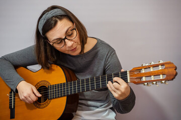 Woman playing classical guitar and singing at home
