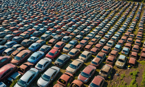 An aerial view of a junkyard filled with rows of old, rusty cars