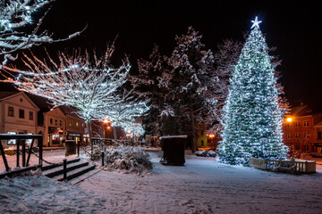 Christmas tree with lights in the town in the evening atmosphere with snow cover