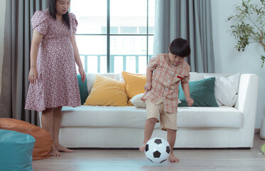 A special child with his mom playing soccer together in the living room of the house