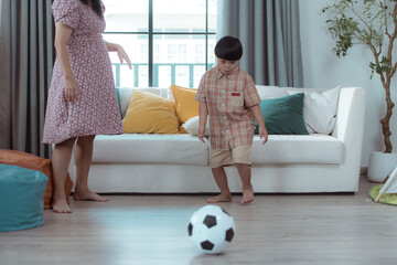 A special child with his mom playing soccer together in the living room of the house