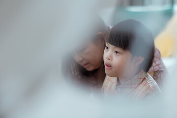 A special child and his mom having fun and relaxing on a holiday together in the living room of the house