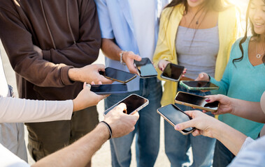 A group of 8 unrecognizable people gather in a circle on the street to connect with each other with mobile phones.Sharing files or information with mobile phones.Mobile connection concept.