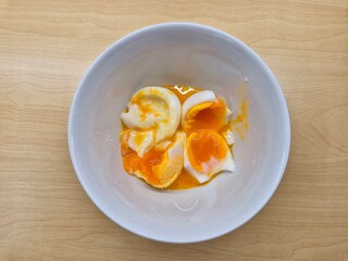 A bowl of eggs with a yellow yolk and a white egg white. The eggs are broken and mixed together....