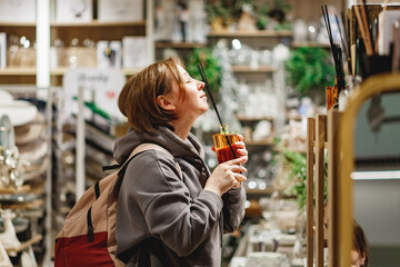 Middle aged woman looking at different casual clothes while shopping in mall
