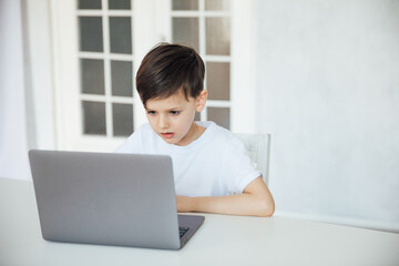 Boy Learning Online With A Laptop At A Table At Home