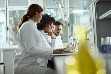 Obraz premium Team of biotechnologists cooperating while reading scientific data on a computer in laboratory.