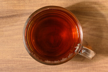 A warm cup of brewed tea resting on a wooden table in a cozy setting