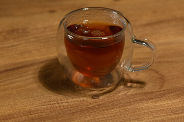 A steaming cup of herbal tea resting on a wooden table during a cozy evening