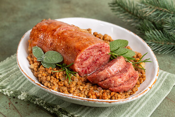 Italian Festive New  Year meal. Traditional cotechino con lenticchie or pork sausage with Lentils cooked with vegetables on a green table.