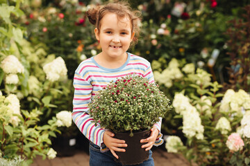 Little cute girl kid buying flowers. Choosing plants in a local garden center.