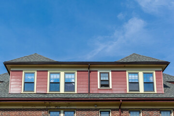 Red clapboard and brick building with dormer windows and hip roof in Brighton, Massachusetts, USA