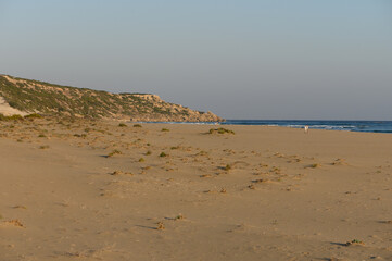 A tranquil evening walk along the sandy beach with gentle waves lapping at the shoreline.