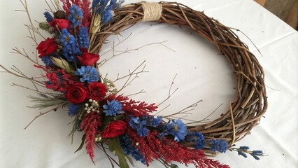 Blue and red floral wreath made from natural materials like willow branches and dried flowers, flowers, branches, twig, foliage, foliage