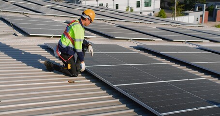 engineer Technician in safety gear installs solar panels on a roof under a clear sky, showcasing renewable energy solutions