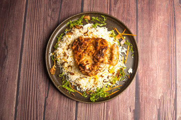 Chicken Ouzi Rice or ozi chicken biryani topping with fried onion served in plate isolated on wooden table top view of turkish food