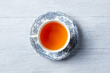 Tea in white cup. Grey wooden background. Close up. Top view.
