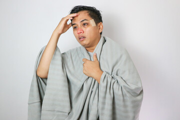 Young asian man standing over white background touching forehead for illness and fever, flu and cold, virus sick.