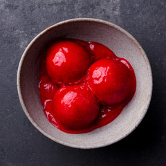 Raspberry ice cream, sorbet, gelato scoops in bowl. Dark background. Close up. Top view.