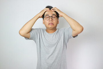 Portrait of young man isolated on gray background, suffering from severe headache, pressing fingers to temples with closed eyes