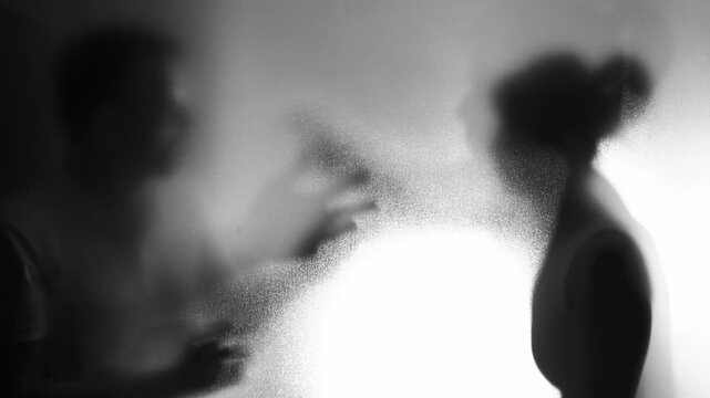 Couple arguing behind the frosted glass