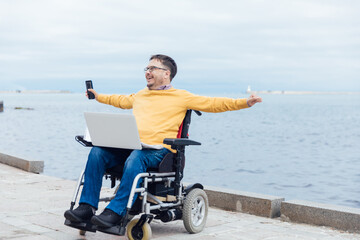 Fototapeta premium A man in a wheelchair on a walk in the city and his hands to the sides