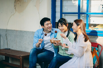 A group of young Asians is having a blast outdoors, laughing, chatting, and enjoying various activities together.