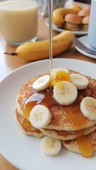 A plate of banana pancakes topped with slices of banana and honey, set on a cozy breakfast table.