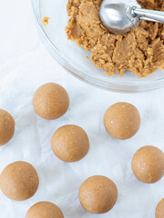 Homemade pumpkin energy balls on white parchment paper. Top view. Raw protein bites, vegan sweet...
