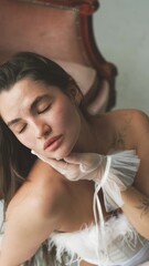 Naklejka premium Portrait of young beautiful model posing in white lingerie, corset, gloves and stockings. Calm cute brunette with long hair in fashionable lingerie. Bride image.