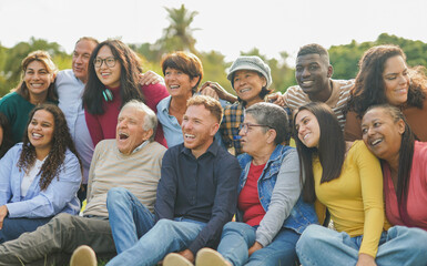 Crowd of happy multiracial people hugging each other outdoor while smiling in front of camera -...