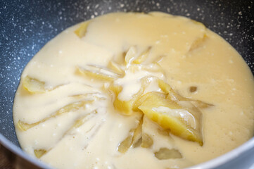 フライパンに並べたリンゴ煮に生地を流し込む