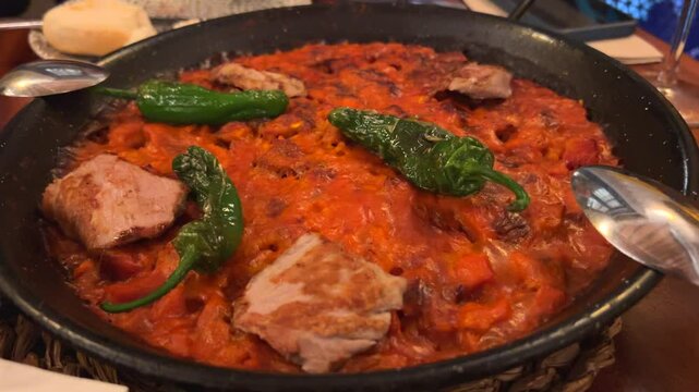 Delicious meat paella with green padron peppers at a Spanish restaurant in Sevilla Spain, traditional Spanish food, famous rice dish, 4K shot