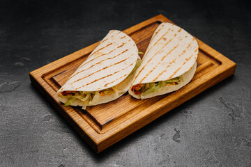 Grilled tortilla wraps with fresh veggies on a wooden board for a quick and tasty meal