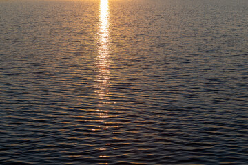 Sunset reflecting on calm waters near a serene coastline during the golden hour