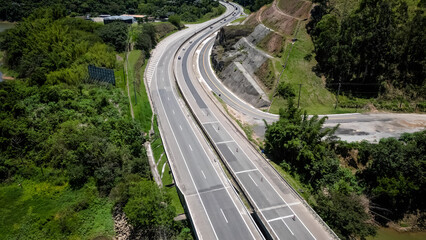 Visto de cima a represa e rodovia coma pontes altas e a natureza ao redor com lindo ceu azul.