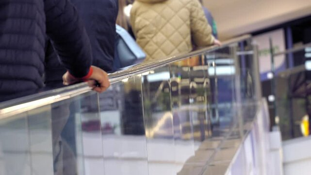 Selective focus close up shot of people hands on moving walkway or sidewalk handrail at airport or shopping mall. Passengers walking on horizontal escalator concept.