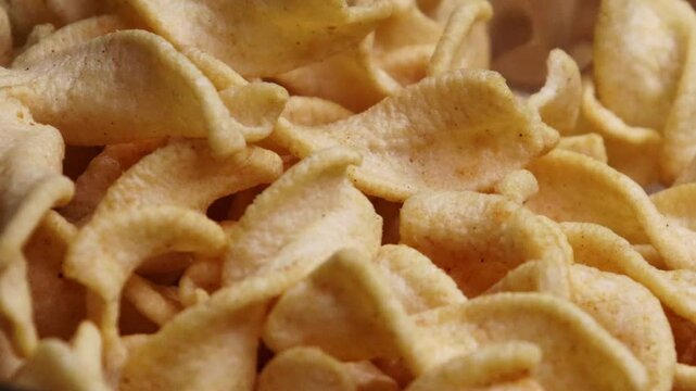 Falling potato chips to the glass bowl close up shot. Unhealthy fast food. Premium Potato Chips Falling Down on Abstract Brown Background at 1000fps.
