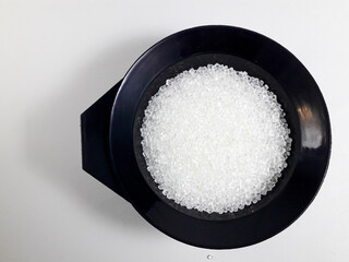 Virgin polycarbonate plastic granules in black cup isolated on white background, one of the main materials in the plastic industry,perfect for catalog design and plastic industry company profiles