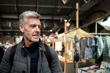 Mature tourist exploring local market stalls and goods on display