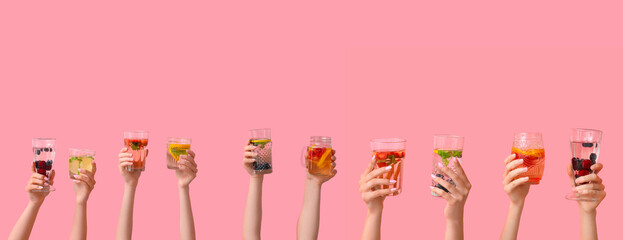 Many hands with infused water on pink background