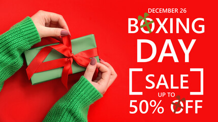 Female hands with Christmas gift box on red background