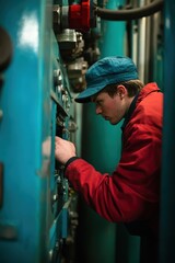 a man in a red jacket and blue hat is working on a machine