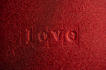 acercamiento a palabra en bajo relieve impresa con tipos sobre textura roja brillante