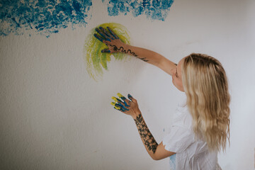 Young Woman Painting a Wall with Yellow and Blue Hand Strokes