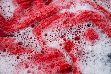 Red Merino Wool Sweater Being Hand Washed in Soapy Water