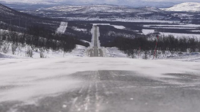 Vent violent balayant la neige sur une route isol&eacute;e en Laponie