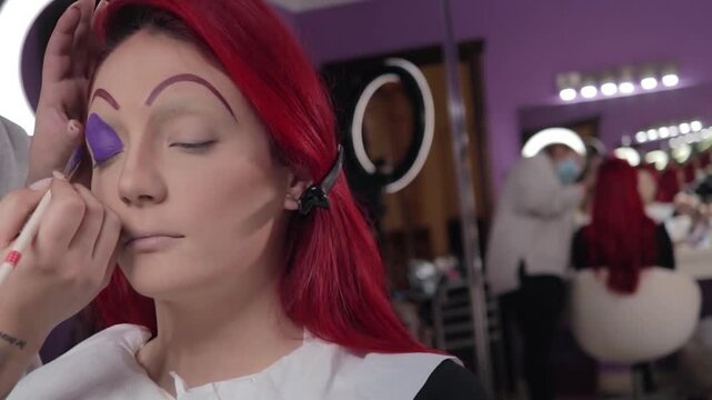 Professional Makeup Artist Applying Character Makeup on Redhead Woman &ndash; Close-up. Maquilladora Profesional Aplicando Maquillaje de Caracterizaci&oacute;n a Mujer Pelirroja &ndash; Primer Plano
